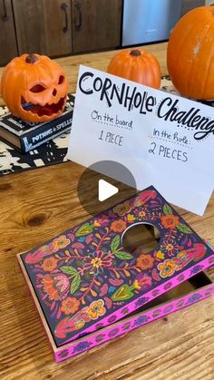 two pumpkins sitting on top of a table next to a sign that says cornhole challenge