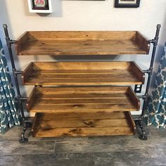 a wooden shelf with metal pipes on the bottom and two shelves below it, against a white wall