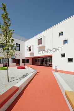 an empty courtyard in front of a large white building with red and yellow trimmings