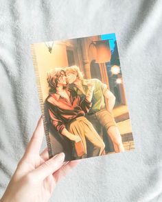 a person holding up a card with an image of a man and woman kissing