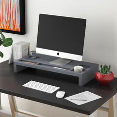 a computer desk with a keyboard, mouse and monitor on it in front of a painting