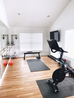 a gym with exercise equipment and yoga mats on the floor, including an exercise bike