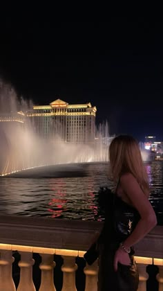 a woman looking at the fountains in front of the las vegas strip hotel and casino