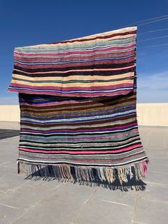 a multicolored striped blanket sitting on top of a cement floor