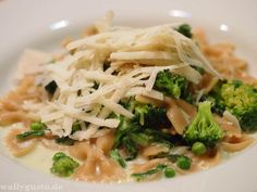 a white plate topped with pasta and broccoli covered in grated parmesan cheese