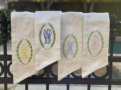 three monogrammed towels hanging on a wrought iron fence