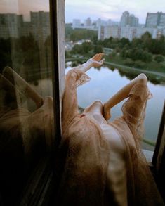 a woman is laying down on the window sill