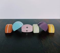 four different colored donuts sitting on top of a wooden table next to each other