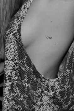 the back of a woman's chest with an infinite symbol tattoo on it