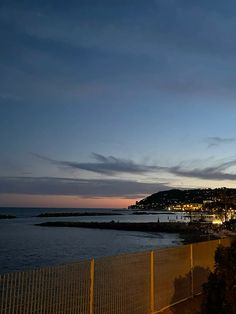 a clock tower is lit up at night by the ocean