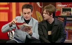 two young men sitting on a couch looking at a piece of paper in front of them