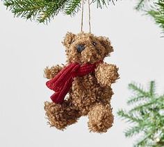 a brown teddy bear ornament hanging from a christmas tree with a red scarf