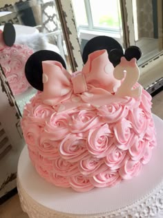 a minnie mouse cake with pink icing and black ears