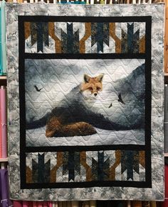 a quilt with a fox on it in front of bookshelves