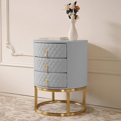 a white vase with flowers sitting on top of a blue dresser next to a wall