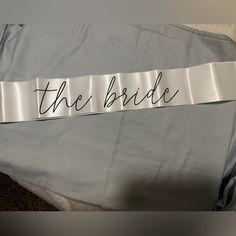 the bride sash is laying on top of a gray shirt that says,'the bride '