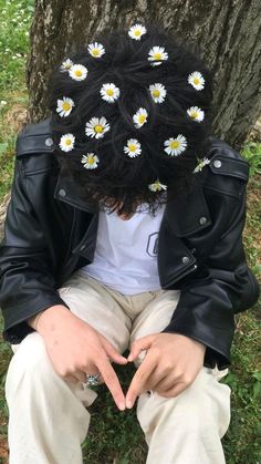 a person sitting in front of a tree with daisies on their head and hands