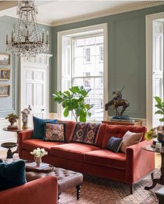 a living room filled with furniture and a chandelier hanging from the ceiling next to two windows