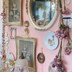 a pink wall with pictures and mirrors on it's sides, flowers hanging from the ceiling