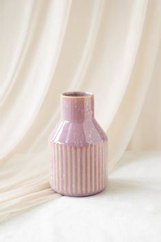 a pink vase sitting on top of a white sheet