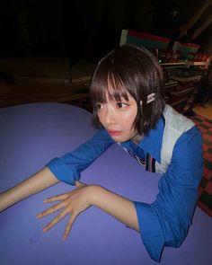 a young woman sitting at a table with her hand on top of the table and looking off into the distance