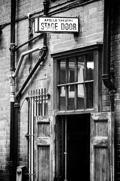 black and white photograph of an old brick building with a sign that says apple theatre stage door