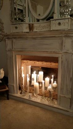 a fireplace with candles lit in front of it and a mirror on the wall above