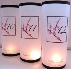 three white vases with pink flowers on them and black trim around the bottom one