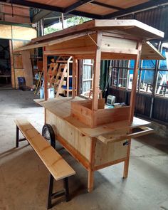 a small wooden structure sitting in the middle of a building with a bench next to it