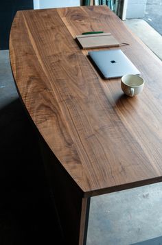 a wooden table topped with a laptop computer next to a coffee cup and saucer