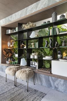 a living room filled with lots of plants and bookshelves next to a wall