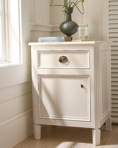 a white cabinet with flowers in a vase on top