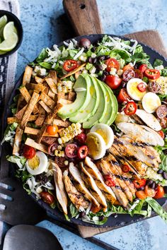 a salad with chicken, avocado, tomatoes and lettuce on it