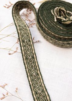 a roll of green and white ribbon next to some dried flowers on top of a table