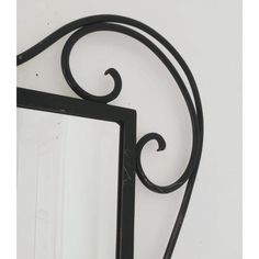 a mirror that is on the wall with an iron frame and curved design around it