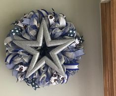 a star wreath hanging on the wall with blue and white ribbon around it's center