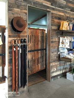 the inside of a store with wooden doors and hats hanging on racks next to it