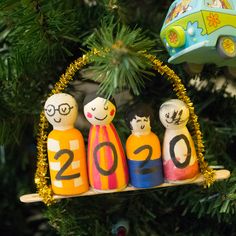 an ornament hanging from a christmas tree with three people on it and a toy car in the background