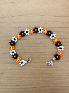 an orange, white and black beaded bracelet on a wooden surface with silver clasp