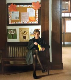 a woman sitting on a bench in front of a bulletin board