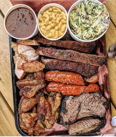 an assortment of meats, macaroni and cheese on a tray with dipping sauce