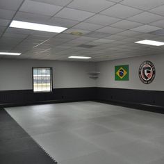 an empty room with two flags on the wall and windows in the center, all painted black