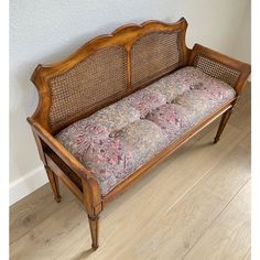 an old wooden bench with floral cushions on it