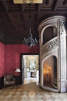 an ornately decorated entry way with chandelier and fireplace in the center, surrounded by pink walls