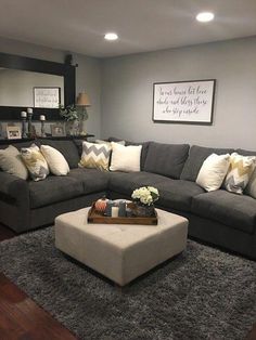 a living room with gray couches and white pillows on the rugs in front of a coffee table