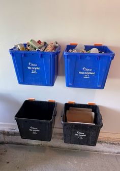 two blue bins are next to each other with recycling labels on the wall behind them