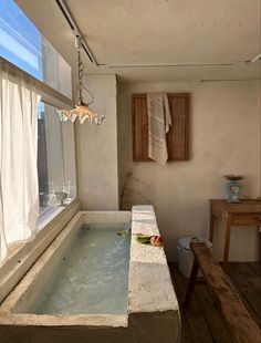 a bath tub sitting in the middle of a room next to a table and window