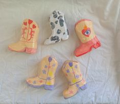 four toy cowboy boots and one cowgirl's boot are on a white sheet