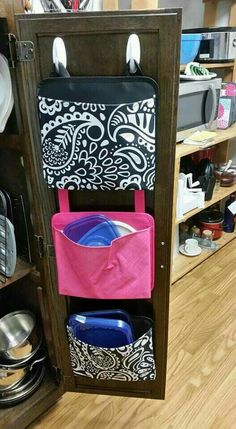 an open cabinet with several items in it and a pink bag hanging from the door