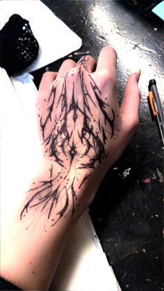 a person's arm with black ink on it and a pen in the other hand